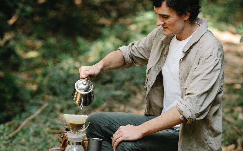 A man pouring water for coffee from the best camping water containers.