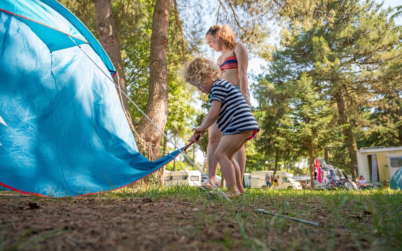 A young girl helping her family set up the tent at their campsite.