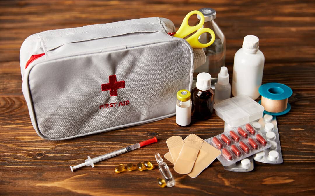 A camping first aid kit displayed on a wooden table.