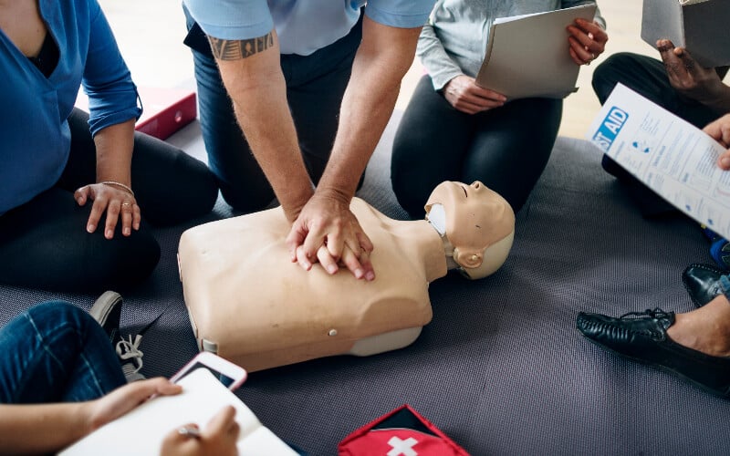 Man teaching CPR on a dummy during a first aid training course.
