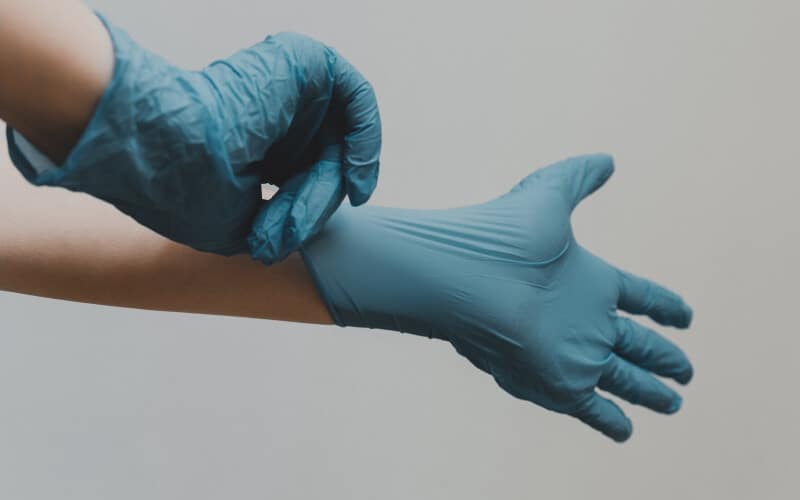 Close up of a person putting disposable medical latex gloves on.