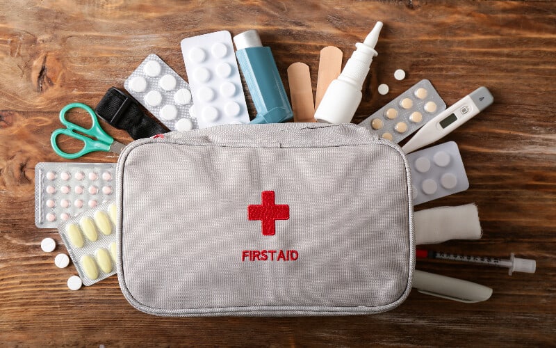A first aid kit with miscellaneous medical items spread around it.