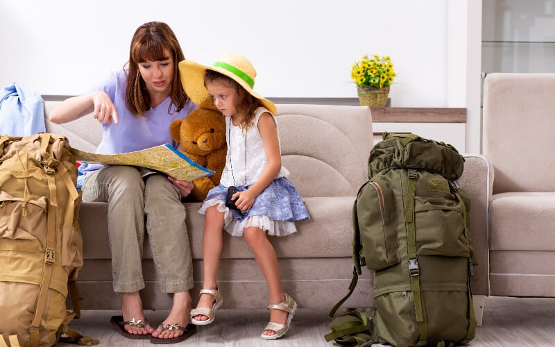 A mother and her daughter sitting on the couch, looking at a map and planning their camping trip.