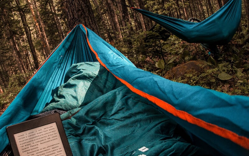 Reading a Kindle while relaxing in a hammock in the woods.