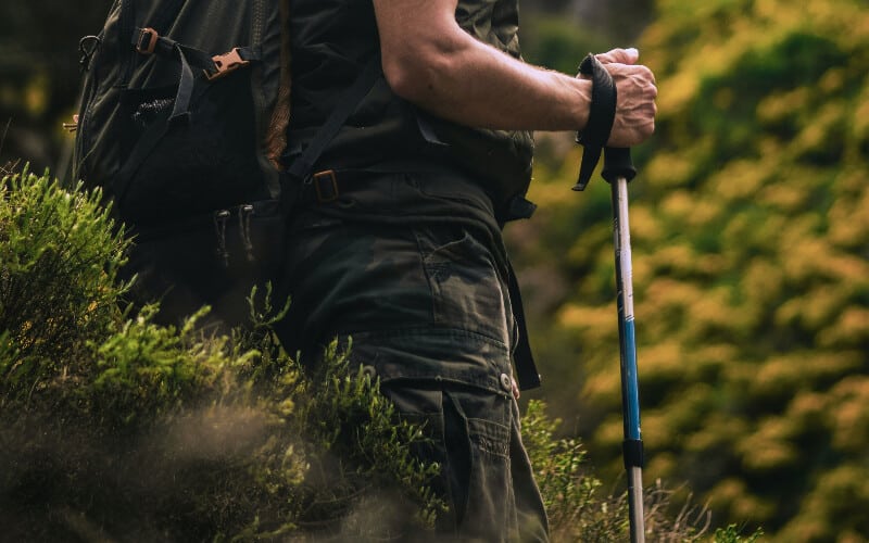 Close up of a man holding a hiking pole during his trek.
