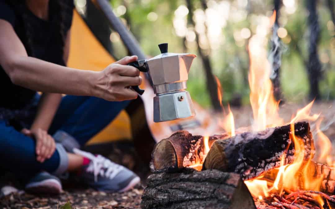 A man next to a campfire enjoying one of the best camping coffee makers of 2023.