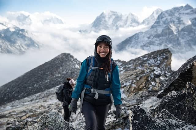 A woman wearing one of the best trekking sunglasses during a hiking trip in the mountains.