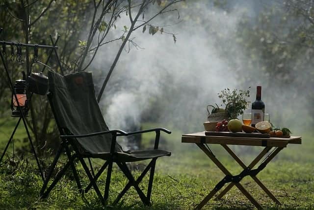 A chair next to a table of fruits and drinks, representing budget-friendly camping recipes.